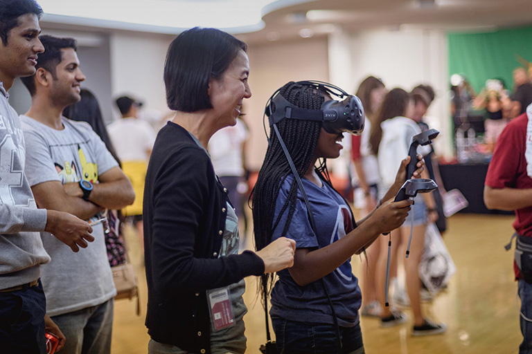 IT Communications staff member helping student with VR headset at the annual Tech Fair event