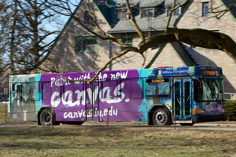 A campus bus wrapped with an ad for Canvas designed by ITCO