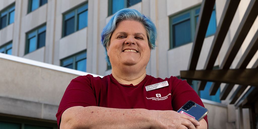 Jody Whiteside holding phone outside a residence hall on IU Bloomington campus