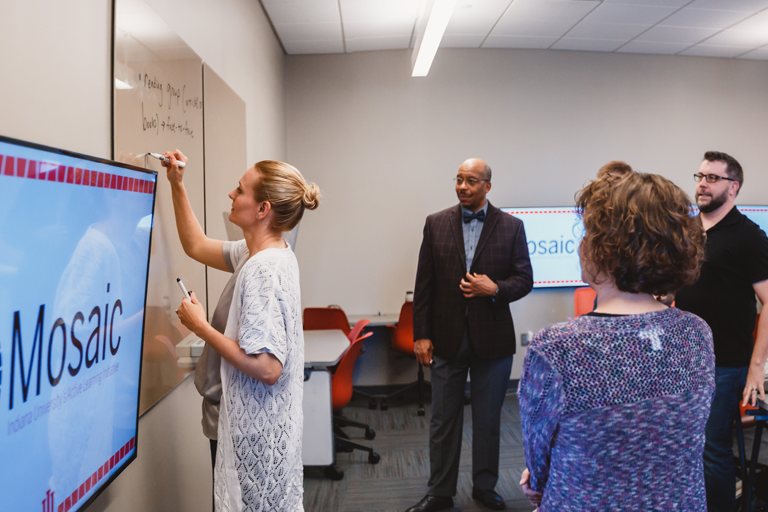 Mosaic faculty fellows collaborating around a whiteboard in a Mosaic classroom
